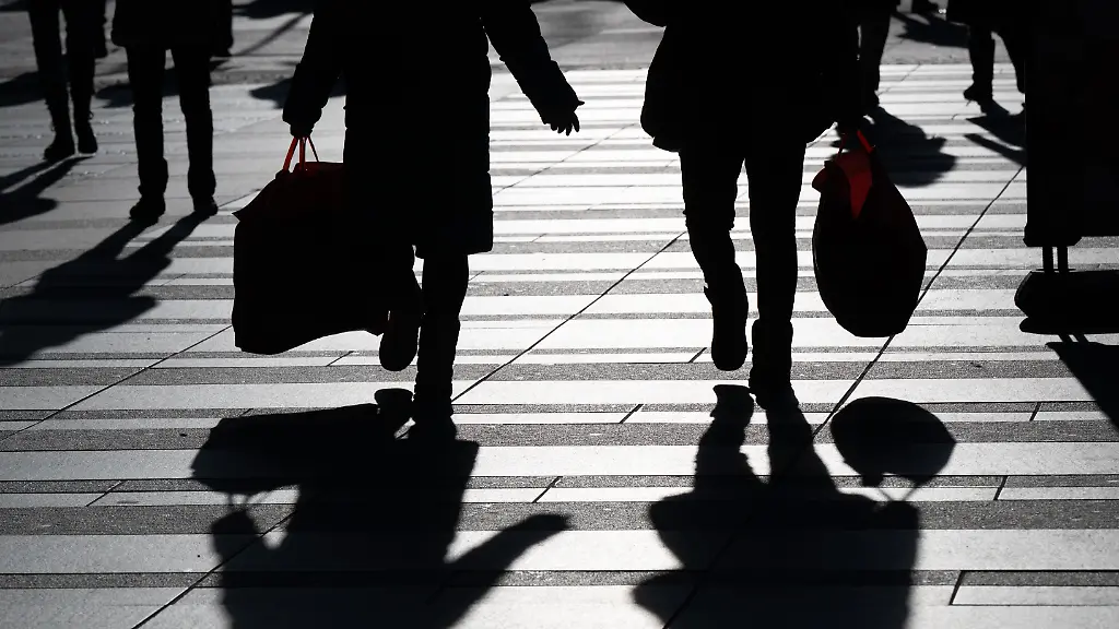 Passanten-mit-Einkaufsbeuteln-zeichnen-sich-im-Gegenlicht-als-Silhouette-ab