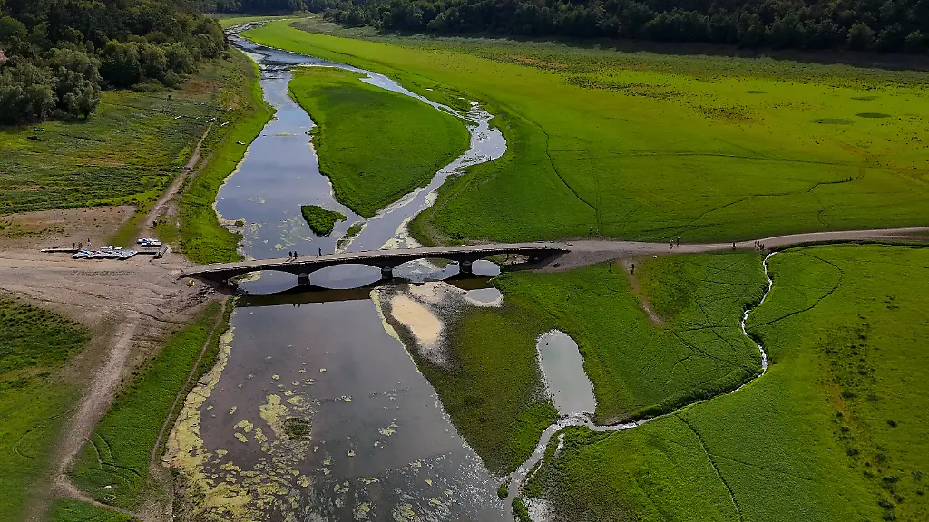 Eine-Drohnenaufnahme-zeigt-die-Aseler-Bruecke-zwischen-schmalen-Wasserlaeufen-und-grossflaechig-freiliegendem-Seegrund-des-Edersees-Der-niedrige-Wasserstand-des-Edersees-legt-grosse-Teile-des-Ufers-sowie-normalerweise-ueberflutete-Bauwerke-und-Landschaftsbereiche-frei
