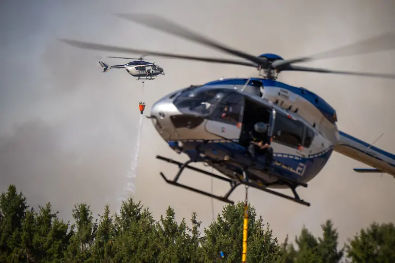 Ein-Helikopter-der-Polizei-wirft-Wasser-aus-einem-Loeschwasser-Aussenlastbehaelter-auf-den-Waldbrand-im-Huertgenwald-Mehrere-Hundert-Hektar-Waldflaeche-stehen-in-Flammen