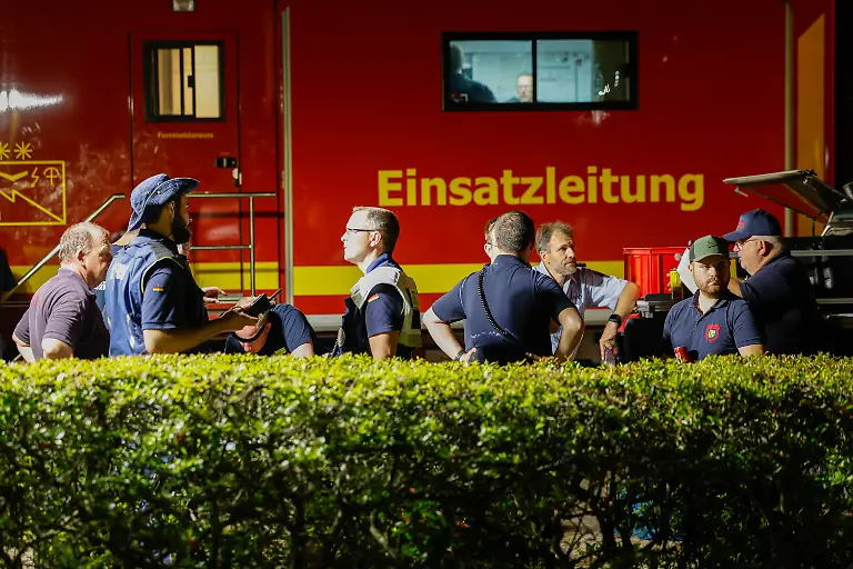 Einsatzkraefte-verschiedener-Organisationen-stehen-zu-einer-Lagebesprechung-zusammen