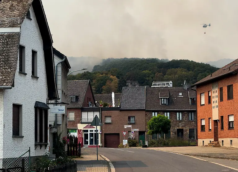 A-helicopter-flies-as-smoke-rises-near-a-residential-area-where-several-hundred-residents-have-been-ordered-to-evacuate-their-houses-following-a-wildfire-in-Huertgenwald-Gey-Germany-August-14-2026