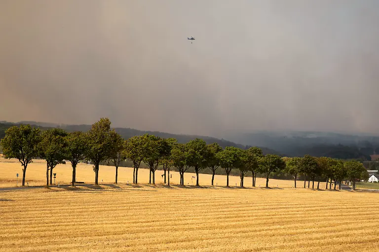 A-helicopter-flies-amid-smoke-as-a-wildfire-approaches-a-residential-area-where-several-hundred-residents-have-been-ordered-to-evacuate-their-houses-near-Huertgenwald-Gey-Germany-August-14-2026
