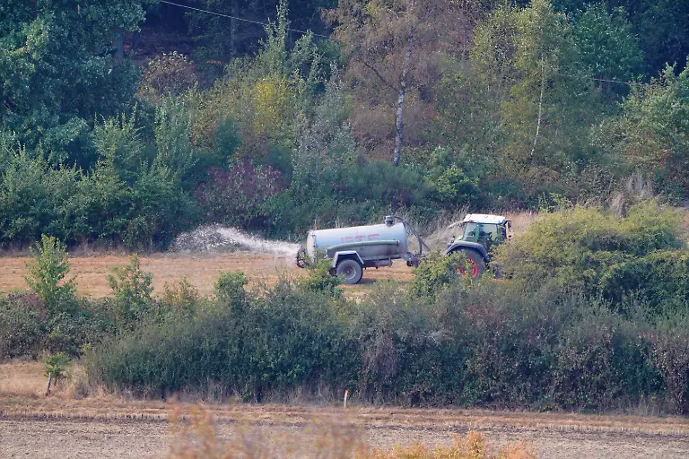 A-farmer-sprays-water-near-a-residential-area-where-several-hundred-residents-have-been-ordered-to-evacuate-their-houses-following-a-wildfire-in-Huertgenwald-Gey-Germany-August-14-2026