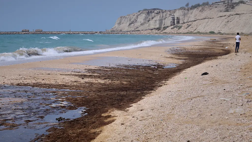 Dunkle-Oelrueckstaende-bedecken-Teile-der-Kueste-am-Shib-Deraz-Strand-auf-der-Insel-Qeschm-waehrend-die-iranischen-Behoerden-die-Ursache-der-Verschmutzung-untersuchen-vor-dem-Hintergrund-anhaltender-kriegsbedingter-Angriffe-auf-Schiffe-und-Infrastruktur-in-und-um-die-Strasse-von-Hormus