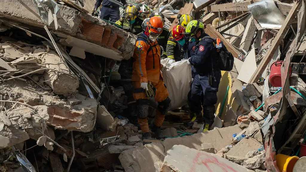 Rettungskraefte-tragen-vier-Tage-nach-dem-Erdbeben-die-Leiche-eines-Opfers-aus-den-Truemmern