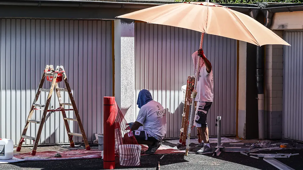 Anstreicher-schuetzen-sich-mit-Sonnenschirm-und-Kopfbedeckung-gegen-die-Sonne-Das-Wetter-bleibt-trocken-und-heiss