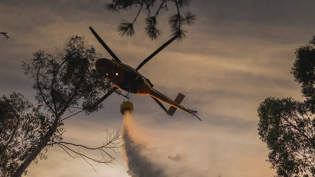 A-helicopter-assists-with-fire-fighting-efforts-during-an-active-wildfire-that-has-scorched-20-hectares-in-Lousame-A-Coruna-Galicia-Spain-on-August-14-2026-after-the-blaze-broke-out-at-around-5-30-pm-in-the-parish-of-Lesende-To-bring-it-under-control-two-technicians-nine-officers-13-fire-crews-eight-motorised-pumps-three-excavators-nine-helicopters-and-four-aeroplanes-have-been-mobilised-so-far-including-resources-from-the-Laza-Firefighting-Brigade-Brif-Photo-by-Agostime-Europa-Press-ABACAPRESS
