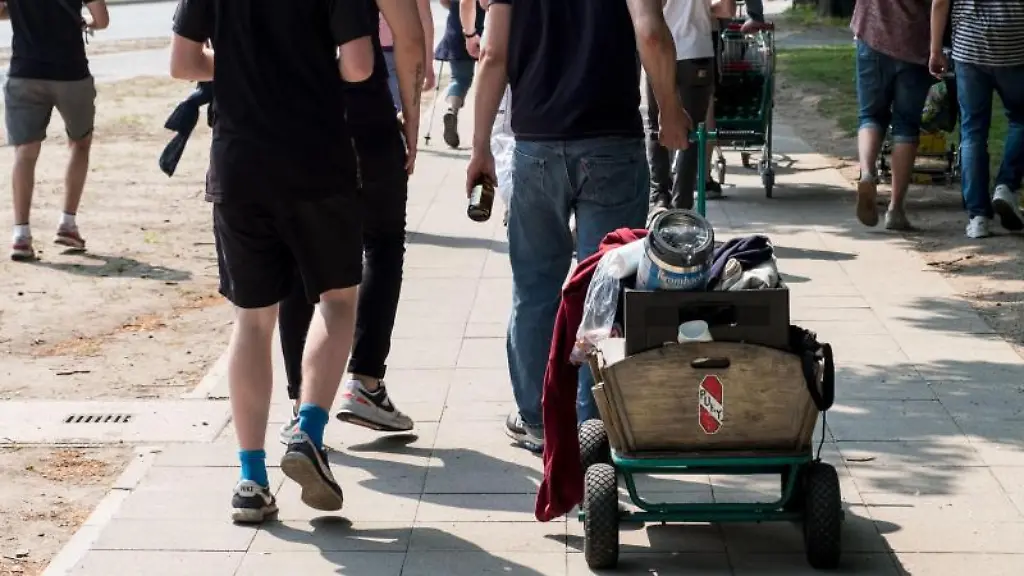 Junge-Leute-ziehen-am-Vatertag-einen-Bollerwagen-und-Einkaufswagen-waehrend-einer-Vatertags-Tour