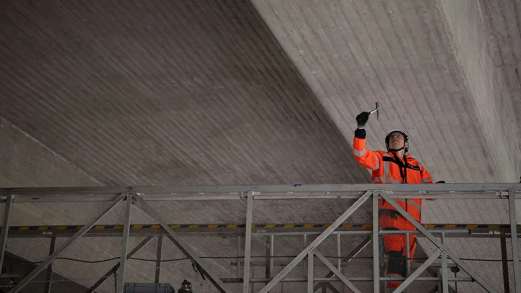Mit-einem-Hammer-klopfen-Pruefer-die-Bruecke-von-unten-ab-um-Schaeden-festzustellen