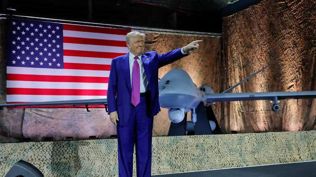 U-S-President-Donald-Trump-gestures-while-delivering-remarks-to-U-S-troops-next-to-a-drone-and-a-U-S-flag-during-a-visit-to-Al-Udeid-Air-Base-in-Doha-Qatar-May-15-2025