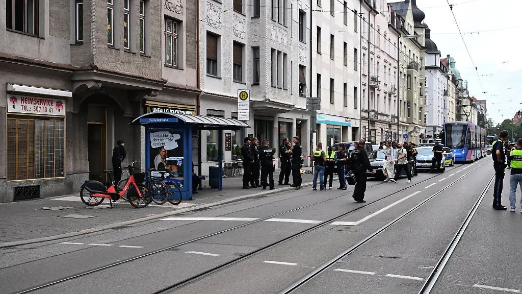 18-08-2026-Bayern-Muenchen-Viele-Polizisten-stehen-am-Tatort-Im-Muenchner-Stadtteil-Schwabing-ist-es-zu-einem-polizeilichen-Schusswaffengebrauch-gekommen-Eine-Person-sei-schwer-verletzt-ins-Krankenhaus-gebracht-worden-berichtete-ein-Polizeisprecher-Warum-geschossen-wurde-sei-noch-unklar-man-stehe-ganz-am-Anfang