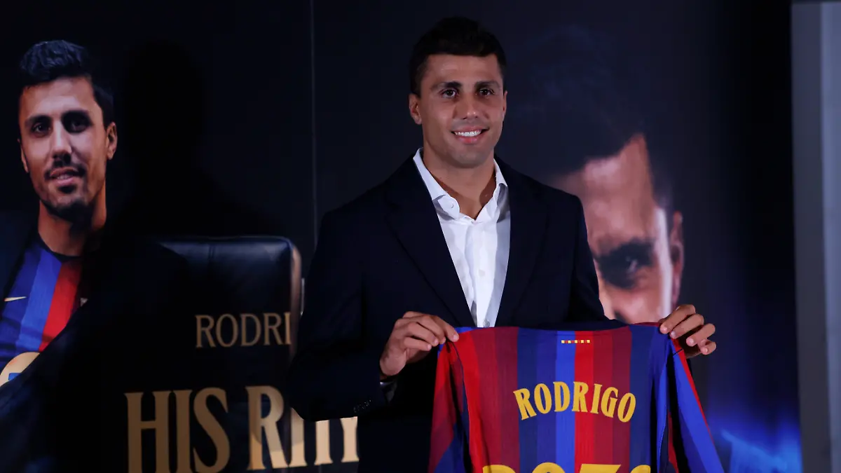 Rodri-laechelt-mit-seinem-neuen-Trikot-waehrend-seiner-Praesentation-als-neuer-Spieler-vom-FC-Barcelona-Wie-Barca-mitteilte-erhaelt-Spaniens-Weltmeisterkapitaen-bei-den-Katalanen-einen-Vertrag-bis-zum-Sommer-2030