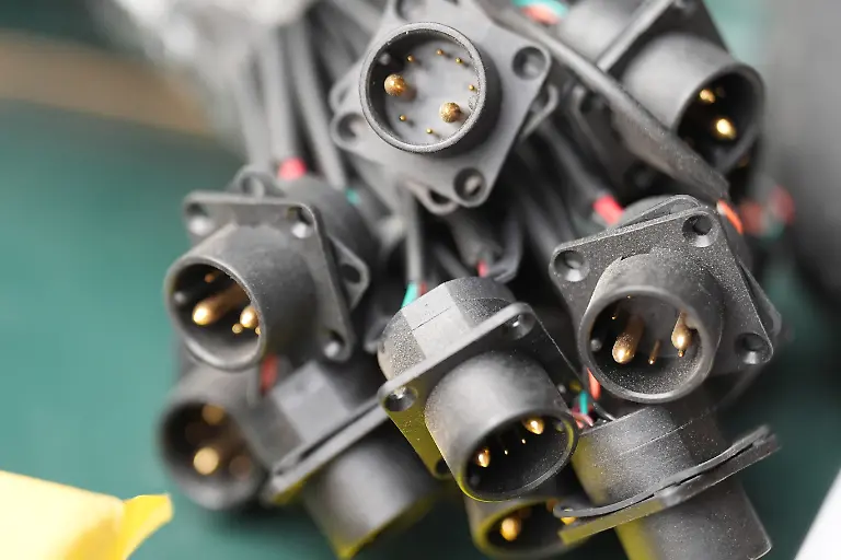 Stecker-fuer-den-Akku-eines-Elektrofahrrads-liegen-in-einer-Werkstatt-auf-einer-Werkbank