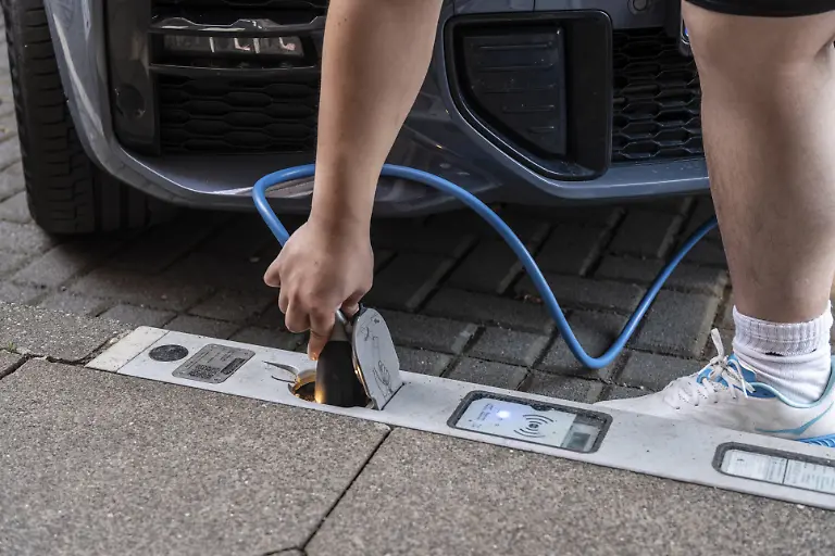 Eine-Person-steckt-ein-Ladekabel-in-einen-Ladebordstein-der-Stadtwerke-Duesseldorf-auf-der-KOe-Duesseldorf-Deutschland