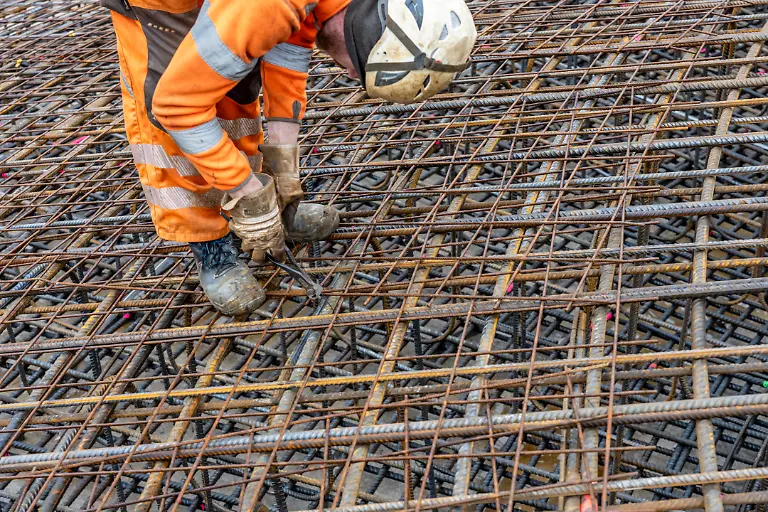 Montage-von-Bewehrungsstahl-fuer-das-Stahlbeton-Fundament-eines-Windrad-ein-Geflecht-aus-Betonstabstahl-und-Betonstahlmatten-Verbindung-der-Stahlelemente-mit-Bindedraht-verdrillen-mit-Monierzange-ueber-100-Tonnen-Armierungsstahl-wurden-verbaut-das-Windrad-wird-ein-Nabenhoehe-von-160-Metern-haben-Teil-eines-neuen-Windpark-im-Sauerland-bei-Balve-NRW-Deutschland
