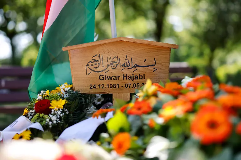 Das-Grab-des-Rapper-Xatar-Giwar-Hajabi-auf-dem-Nordfriedhof-in-Bonn-Die-Flagge-von-Kurdistan-weht-im-Wind-Angehoerige-haben-Kraenze-niedergelegt-Zahlreiche-Fans-und-Anwohner-pilgern-zu-der-Grabstaette-um-ihre-letzte-Ehre-zu-erweisen-Der-Bonner-Gangster-Rapper-war-im-Mai-2025-mit-nur-43-Jahren-tot-in-seiner-Koelner-Wohnung-aufgefunden-worden-Bonn-15-05