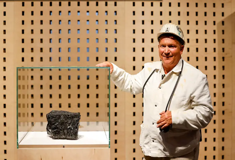 Der-ehemalige-Bergmann-Juergen-Jakubeit-steht-neben-der-Vitrine-in-der-Dauerausstellung-im-Haus-der-Geschichte-der-Bundesrepublik-Deutschland-in-der-der-rund-sieben-Kilogramm-schwere-Kohlebrocken-aus-der-Zeche-Prosperitaet-Haniel-dem-letzten-deutschen-Steinkohlenbergwerk-in-Bottrop-liegt