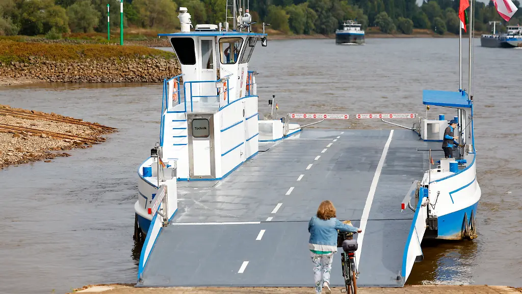 Eine-Radfahrerin-nimmt-die-erste-Faehre-zum-anderen-Rheinufer-Nach-Trockenheit-und-Niedrigwasser-kann-die-Rheinfaehre-zwischen-dem-Duesseldorfer-Sueden-und-Zons-Dormagen-wieder-den-Faehrbetrieb-aufnehmen