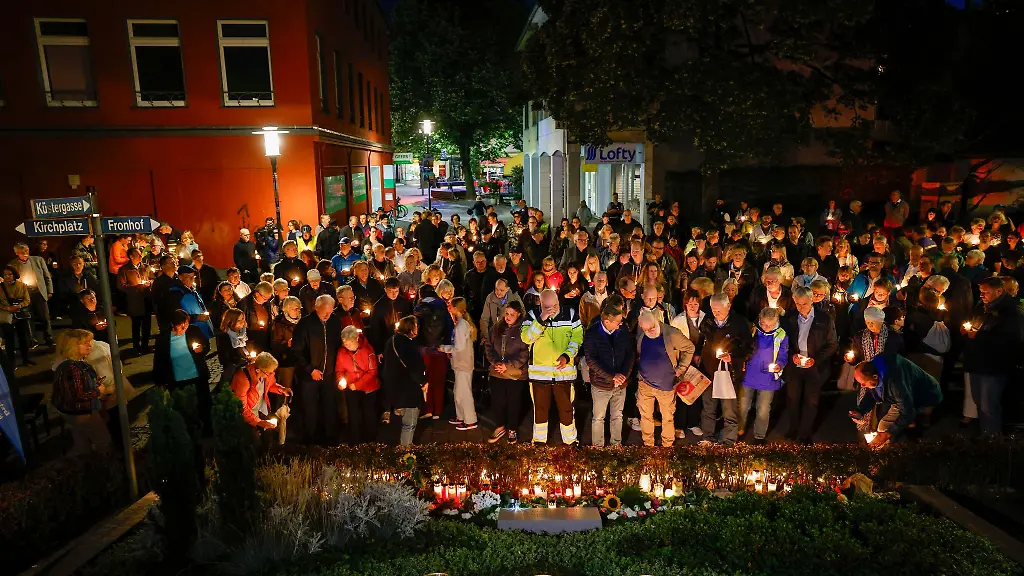 Bei-der-Trauerfeier-an-der-Gedenktafel-zum-ersten-Jahrestag-des-Anschlags-halten-Teilnehmer-brennende-Kerzen-in-den-Haenden