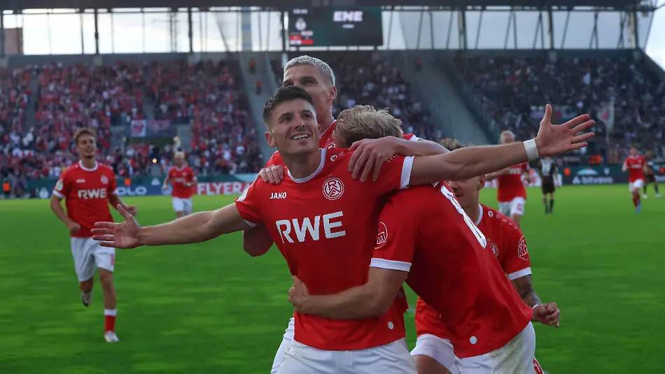 Semir-Telalovi-17-Rot-Weiss-Essen-reisst-die-Arme-weit-aus-und-feiert-einen-Treffer-mit-seinen-Mitspielern-im-Stadion-an-der-Hafenstrasse-Die-vollbesetzte-Tribuene-im-Hintergrund-unterstreicht-die-Stimmung-beim-Heimspiel-Semir-Telalovi-17-Rot-Weiss-Essen-jubelt-mit-Teamkollegen-Semir-Telalovi-No-17-Rot-Weiss-Essen-throws-his-arms-wide-and-celebrates-a-goal-with-his-teammates-at-the-stadium-on-Hafenstrasse-The-packed-stands-in-the-background-highlight-the-atmosphere-at-the-home-game-Semir-Telalovi-No-17-Rot-Weiss-Essen-celebrates-with-his-teammates