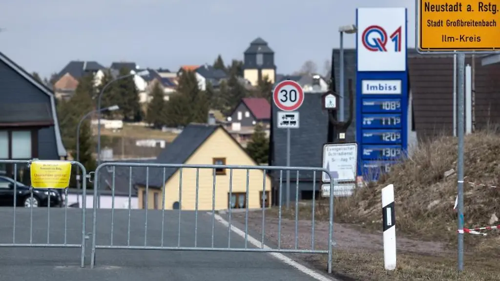 Ein-Sperrzaun-mit-Schild-an-der-Ortszufahrt-weist-auf-die-Quarantaene-des-Ortes-hin
