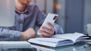 Mann mit Handy am Schreibtisch