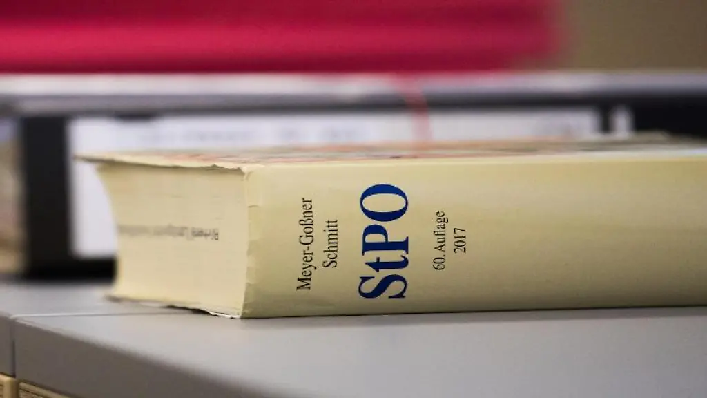 Eine-Strafprozessordnung-liegt-neben-Akten-auf-einem-Tisch
