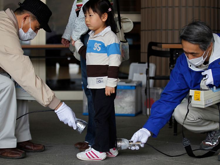 Vor einem Evakuierungszentrum in Fukushima wird eine Dreijährige auf Strahlung untersucht.