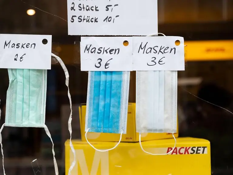 Masken-in-verschiedenen-Varianten-haengen-in-einem-Schaufenster-eines-Kioskes-mit-angeschlossenem-DHL-Paketshop