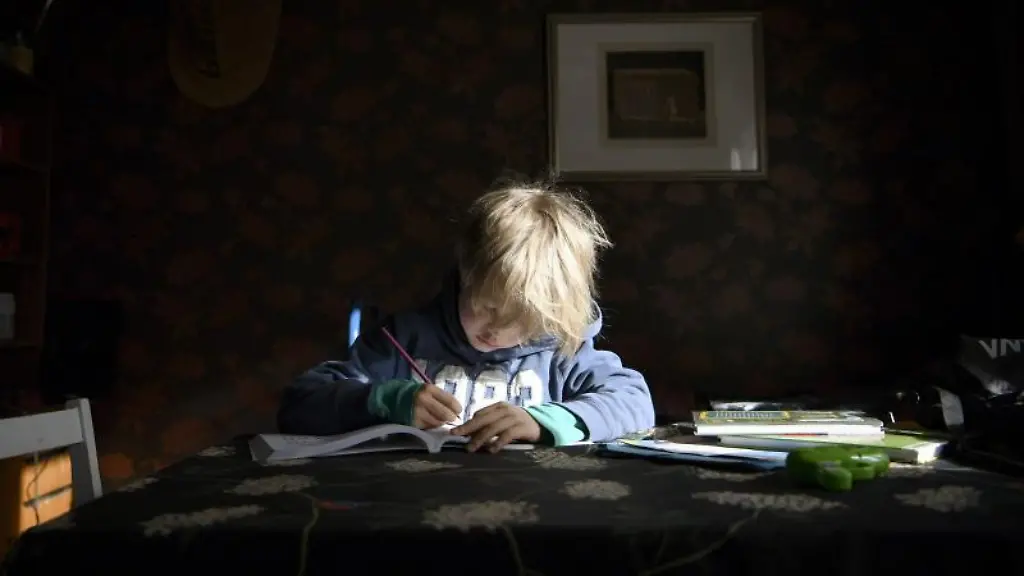 Ein-Junge-sitzt-zu-Hause-an-einem-Tisch-und-schreibt-in-einem-Schulheft