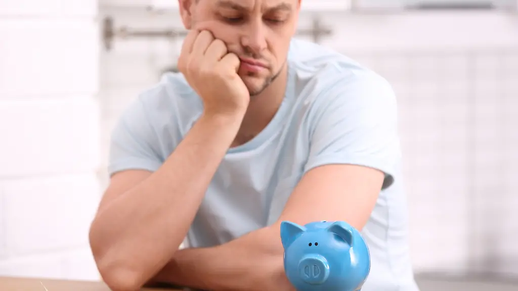 Mann neben Sparschwein