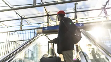 Mann mit Koffer auf Rolltreppe