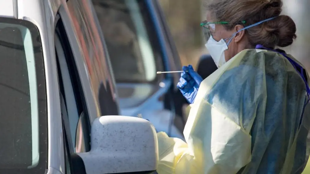 Eine-Aerztin-nimmt-einen-Abstrich-bei-einer-Patientin-die-mit-ihrem-PKW-an-einem-Drive-in-fuer-Corona-Tests-steht