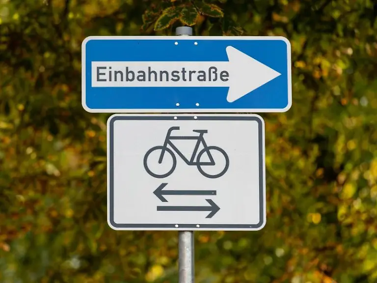 Ein-Verkehrsschild-Einbahnstrasse-und-eines-fuer-Radverkehr-in-wechselseitiger-Richtung