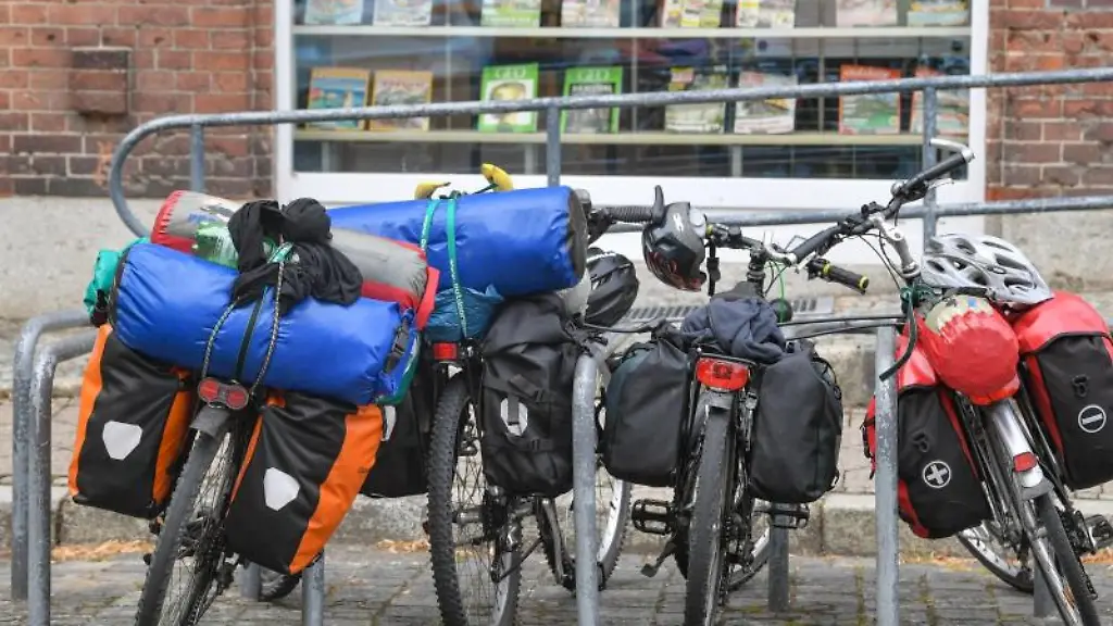 Vier-Fahrraeder-beladen-mit-Gepaeck-stehen-an-einem-Fahrradstaender