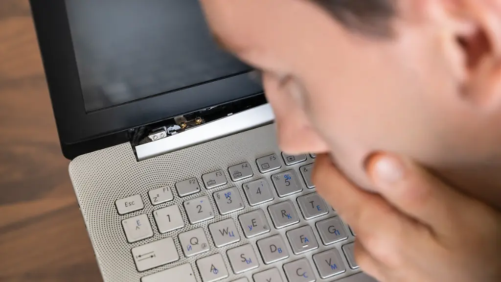 Mann schaut auf kaputten Laptop
