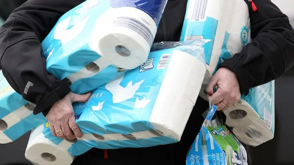 Ein-Mann-traegt-eingekauftes-Toilettenpapier-aus-einem-Supermarkt