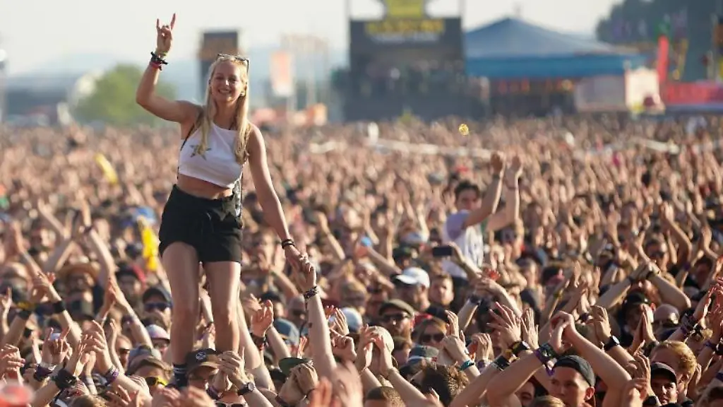 Eine-junge-Frau-steht-beim-Auftritt-der-US-amerikanischen-Punkband-Rise-against-vor-der-Hauptbuehne-des-Musikfestival-Rock-am-Ring-auf-den-Schultern-eines-Zuschauers