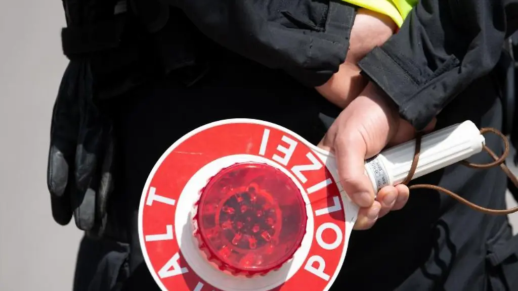 Ein-Polizist-haelt-eine-Kelle-in-den-Haenden