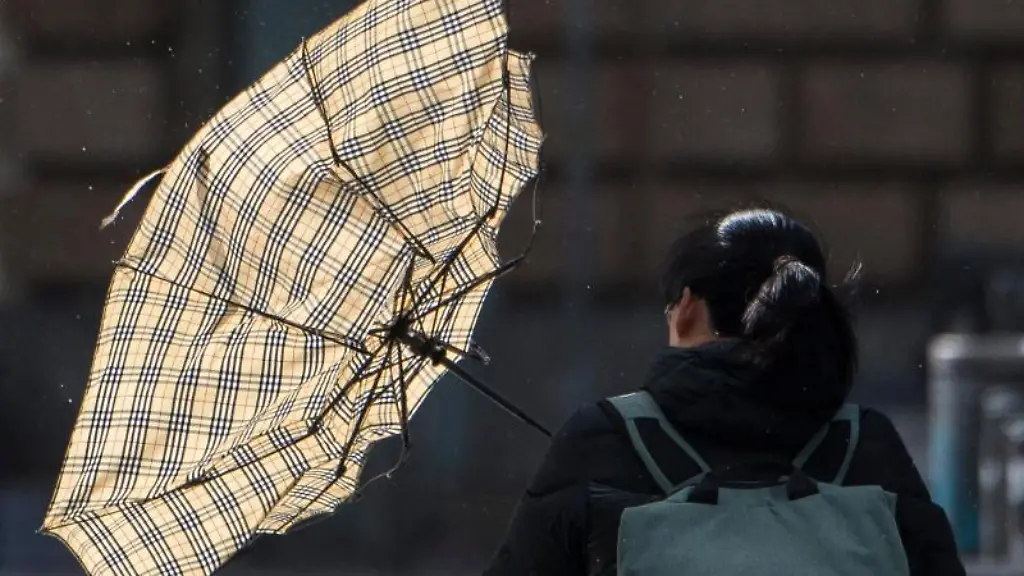 Eine-heftige-Sturmboee-erfasst-den-Schirm-einer-Frau