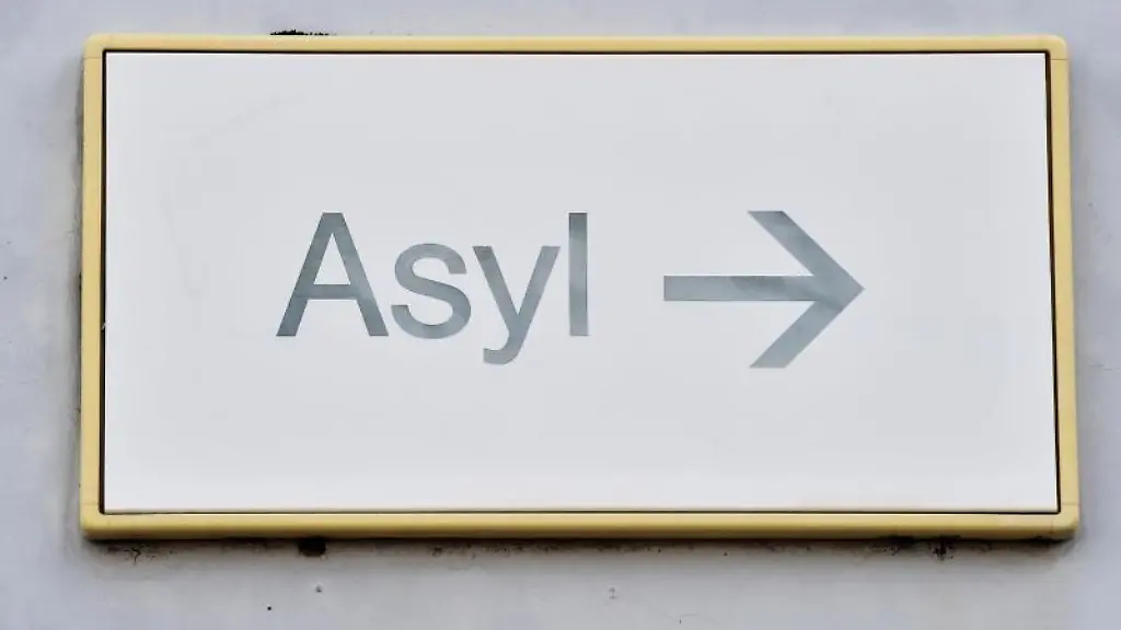 Ein-Schild-mit-der-Aufschrift-Asyl-haengt-in-der-Landeserstaufnahme-fuer-Asylbewerber-an-einer-Wand