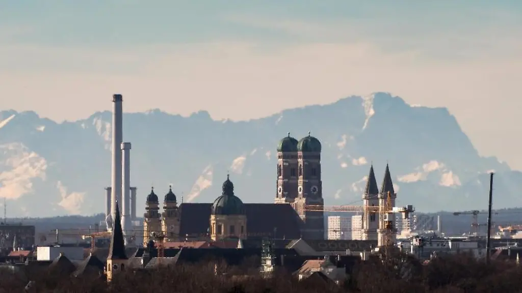 Die-Skyline-der-bayerischen-Landeshauptstadt-ist-vor-der-Kulisse-der-etwa-90-Kilometer-entfernten-Alpen-mit-der-Zugspitze