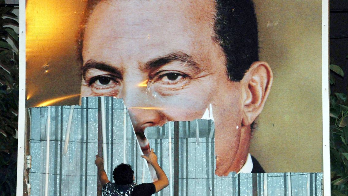 In Alexandria wird ein Plakat von Mubarak abgerissen.
