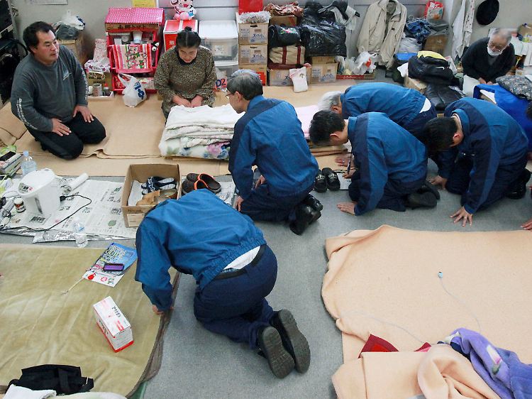 Tepco-Chef Shimizu und andere Konzern-Vertreter bitten Bewohner einer Notunterkunft um Verzeihung.