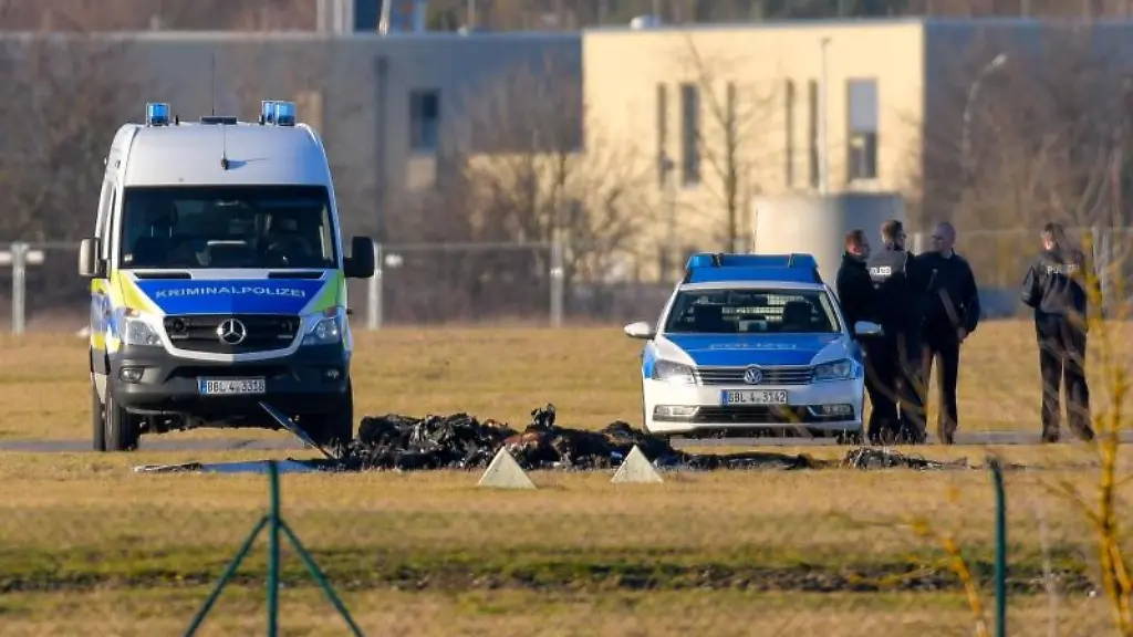 Zwischen-Polizeifahrzeugen-sind-verkohlte-Reste-eines-Kleinflugzeuges-auf-dem-Flugplatze-Strausberg-zu-sehen