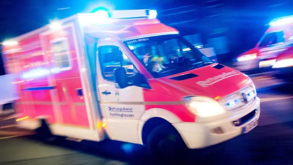 Ein-Rettungswagen-faehrt-mit-Blaulicht-durch-eine-Strasse