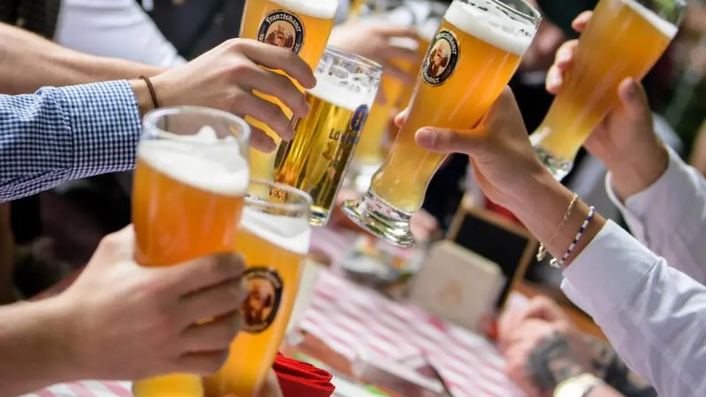 Eine-Maennergruppe-stoesst-im-Biergarten-eines-Wirtshauses-an-der-Isar-mit-ihren-Weissbierglaesern-an
