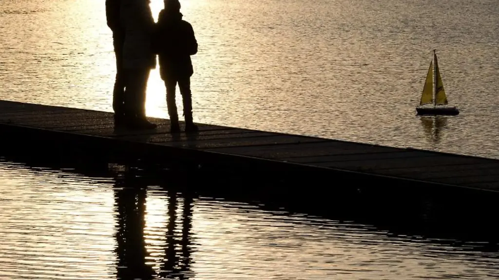 Eine-Familie-schaut-auf-einem-Steg-einem-ferngesteuerten-Segelboot-nach