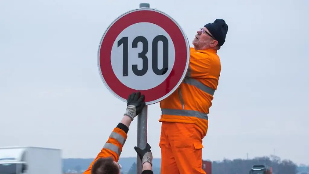 Strassenwaerter-montieren-ein-Verkehrsschild-fuer-die-Geschwindigkeitsbegrenzung-130-an-einer-Autobahn