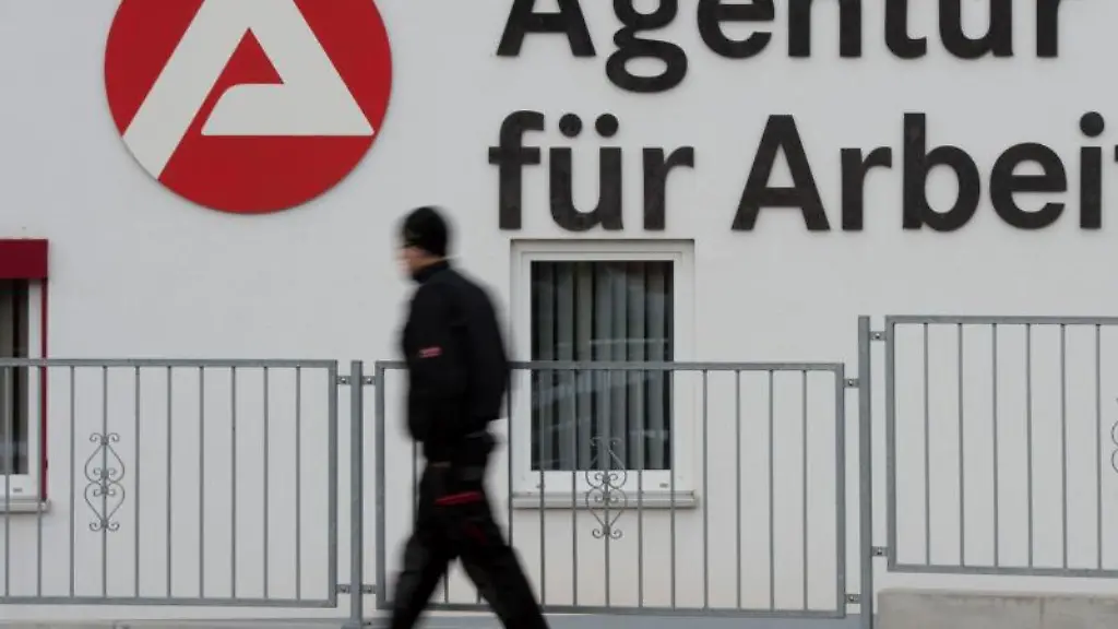 Ein-Passant-geht-an-dem-Logo-der-Agentur-fuer-Arbeit-vorbei
